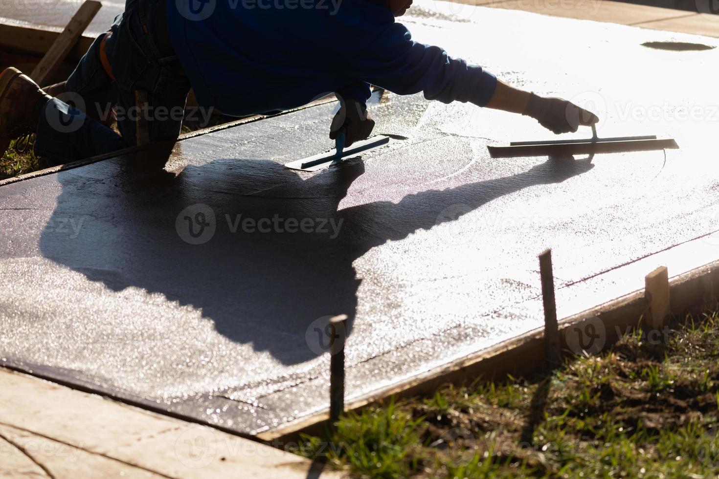 trabalhador da construção civil alisando cimento molhado com ferramentas de espátula foto