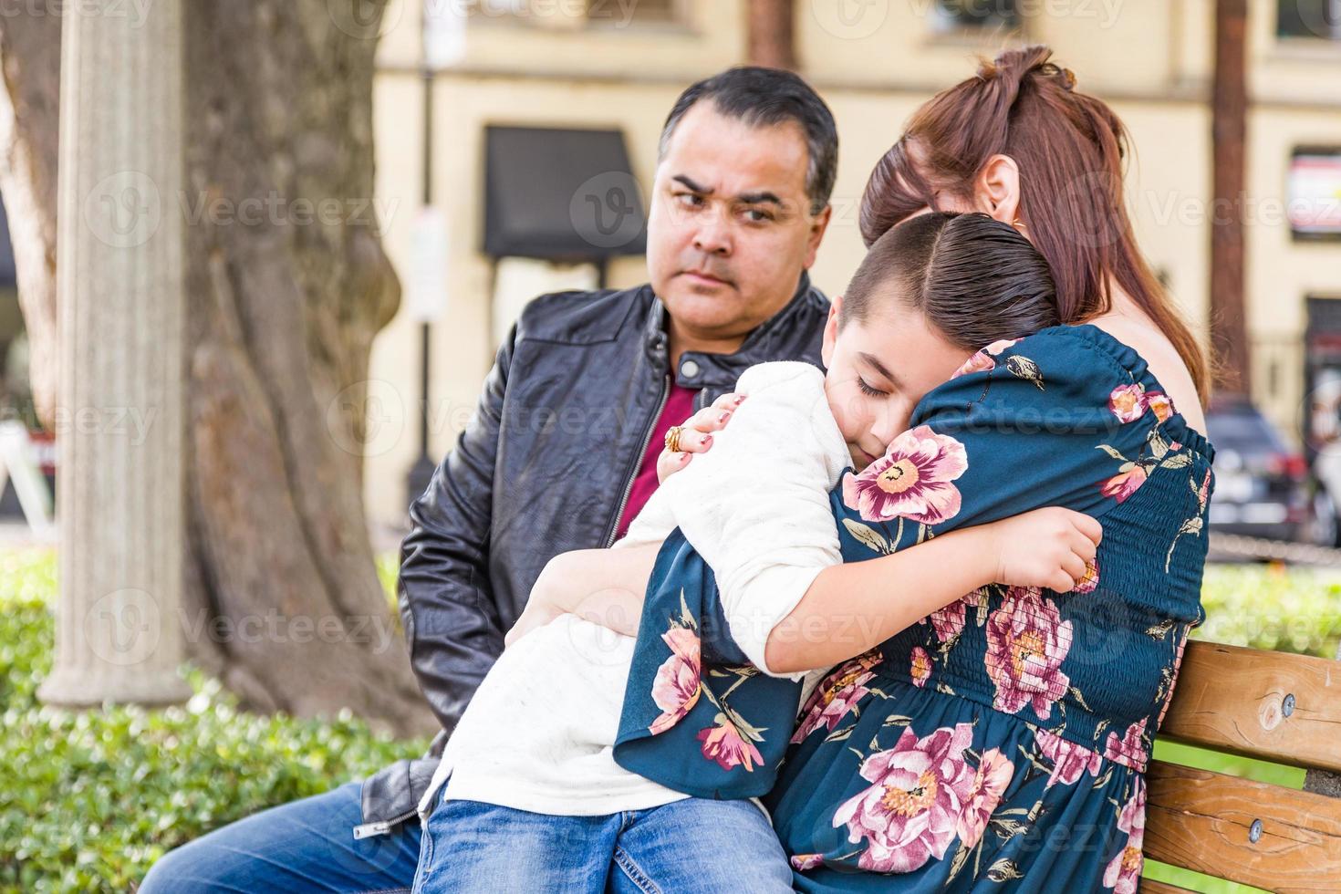 mãe caucasiana e pai hispânico consolando filho mestiço ao ar livre foto