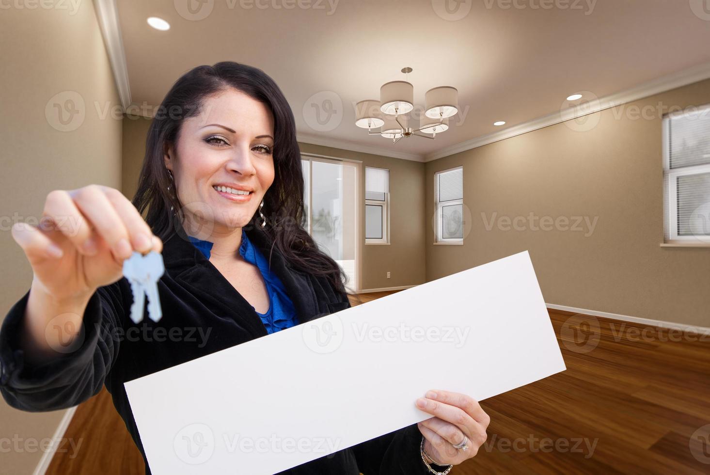 mulher hispânica com chaves de casa e sinal em branco no quarto vazio da casa. foto