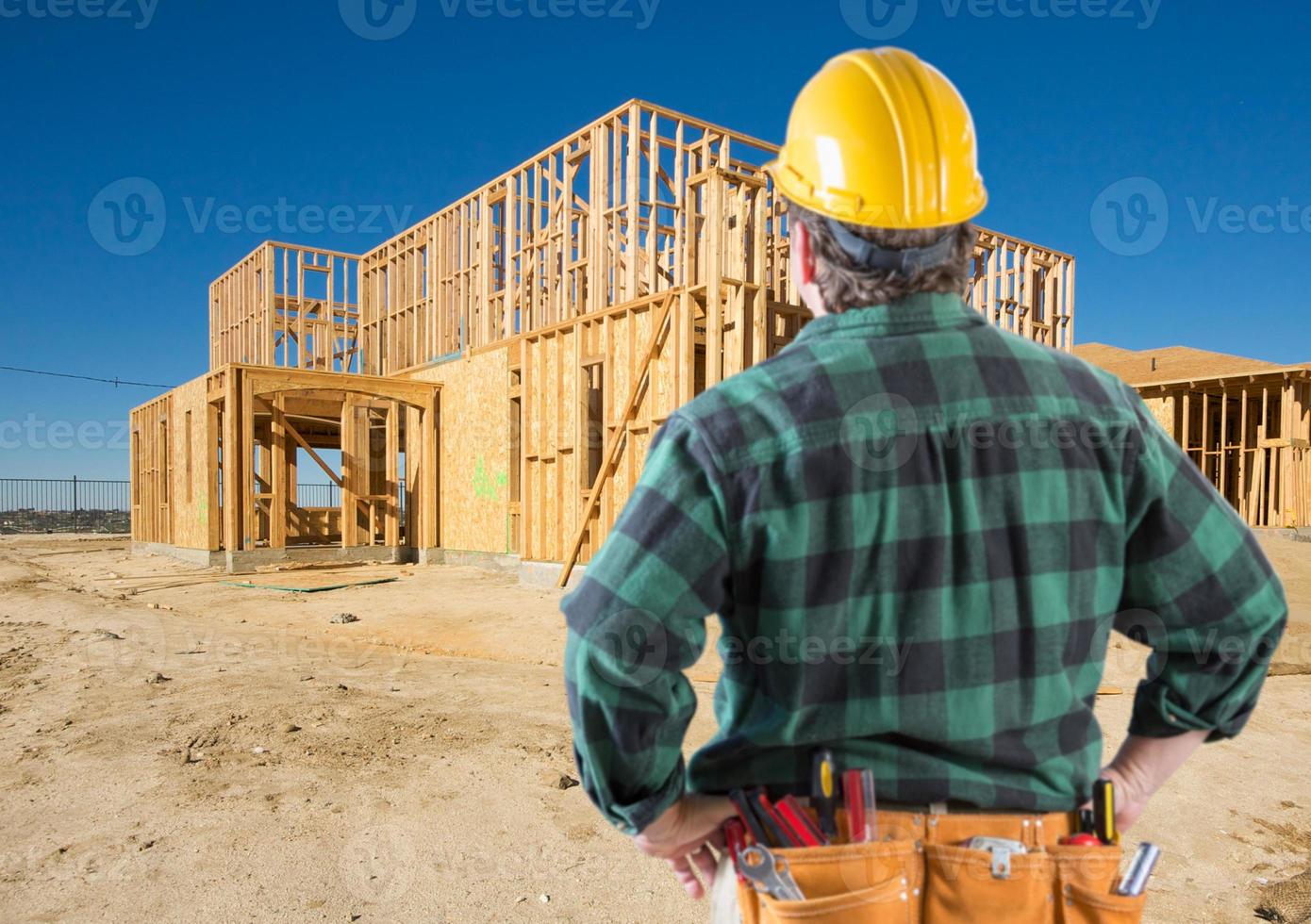 empreiteiro com capacete olhando para o enquadramento de casa nova no canteiro de obras. foto