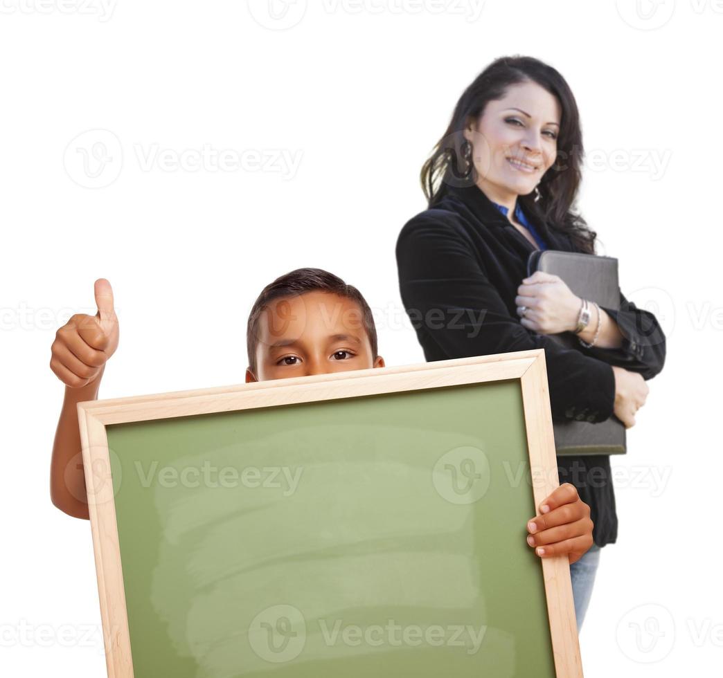 menino com polegares para cima, quadro de giz em branco e professor atrás foto