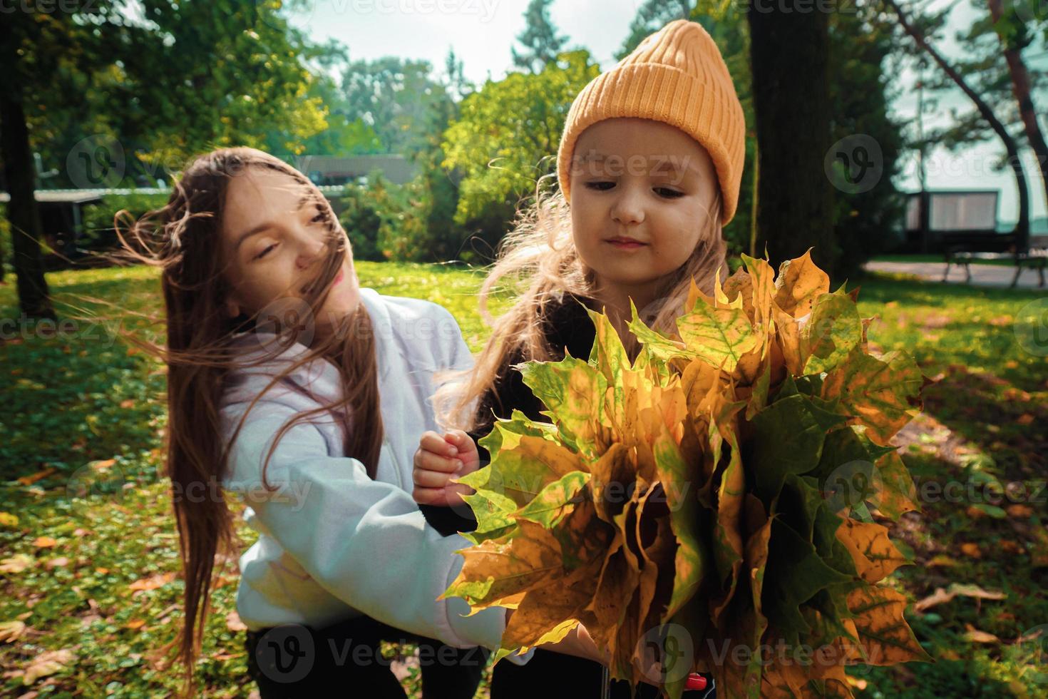 mãe com filha coleta um buquê de folhas de outono no parque foto