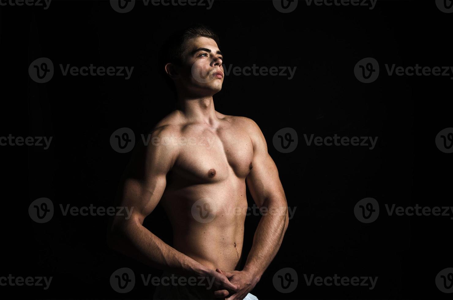 homem de corpo muscular em fundo preto foto