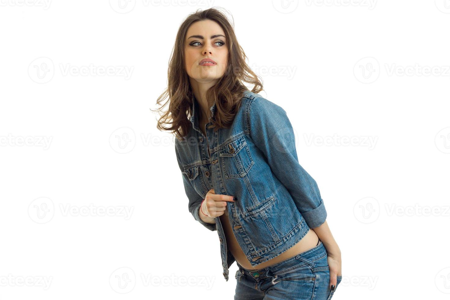 bela jovem morena posando na câmera inclinando-se para a frente em uma jaqueta jeans foto