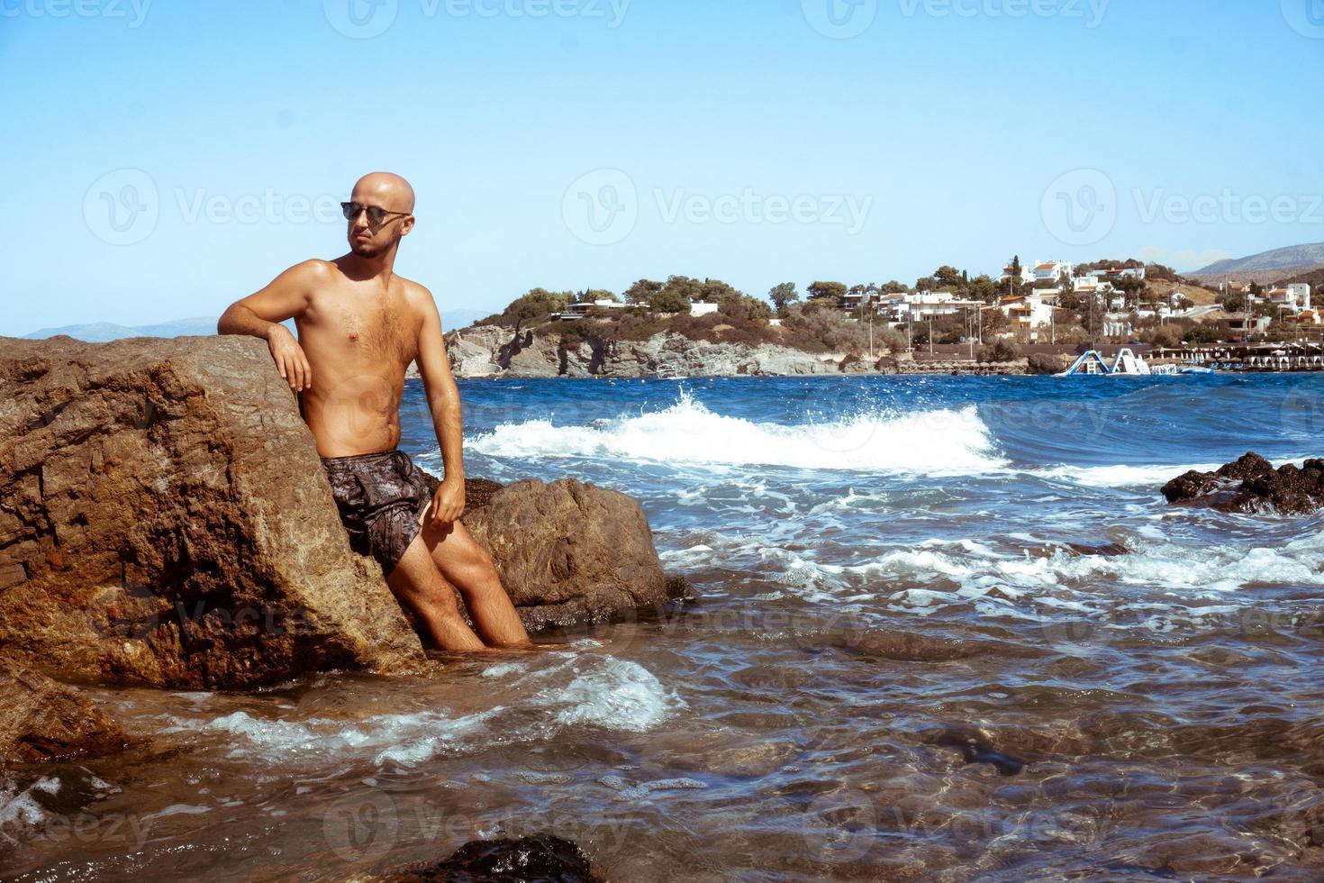 homem bonito na costa rochosa marinha foto