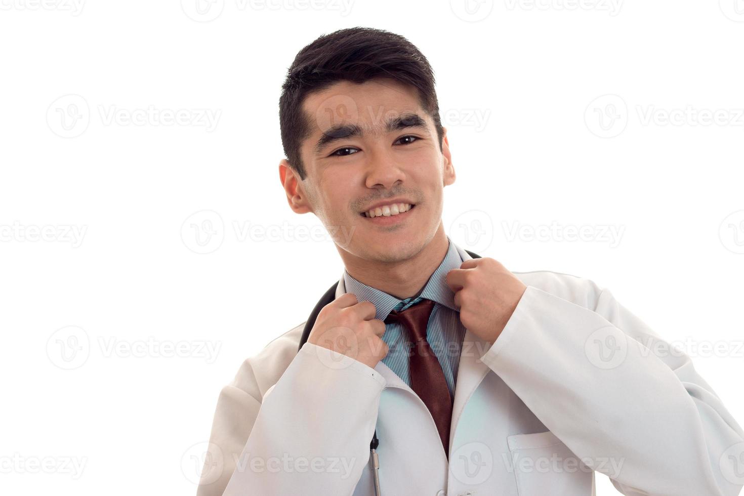 retrato de jovem médico masculino alegre com estetoscópio de uniforme isolado no fundo branco foto