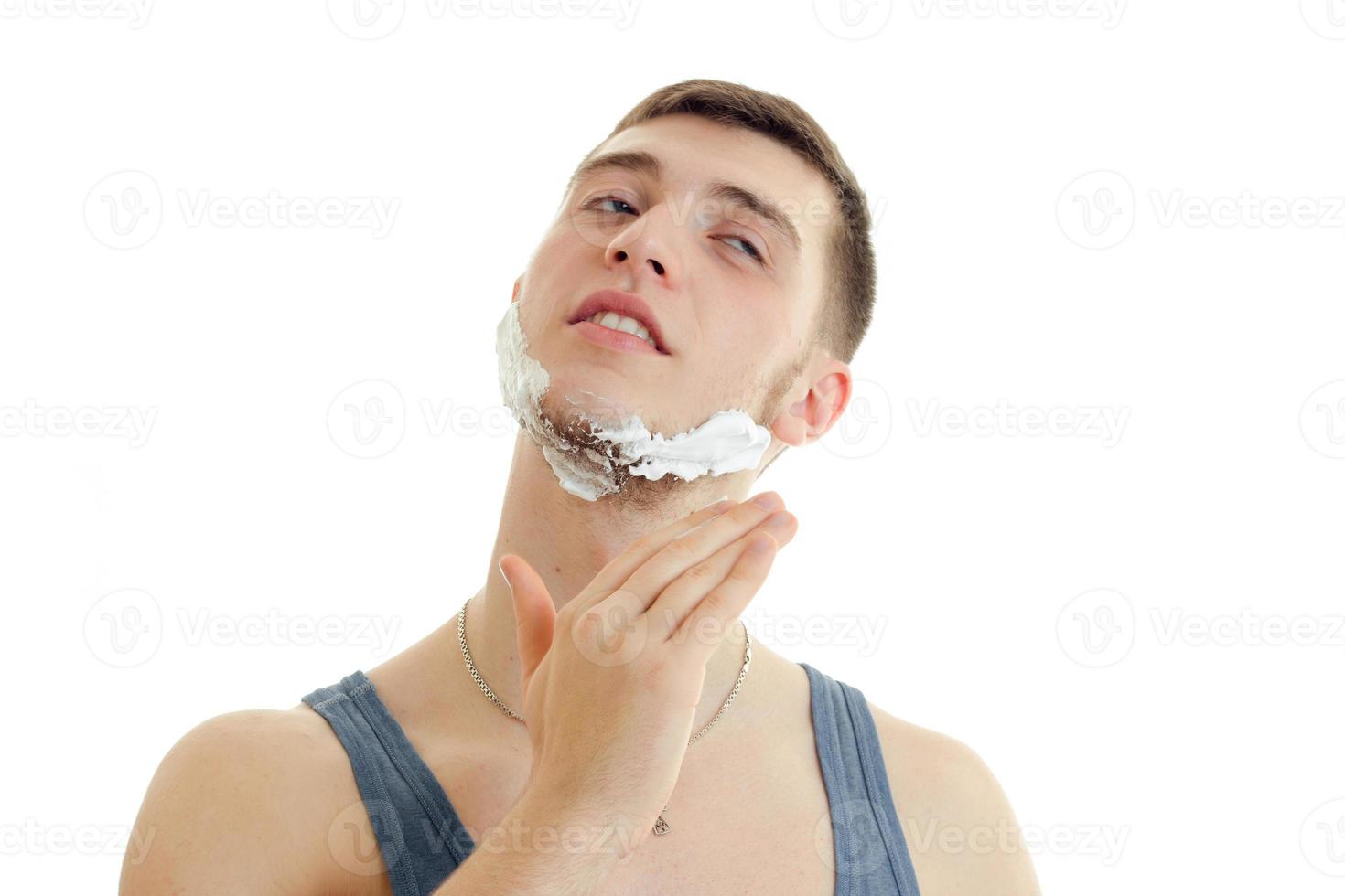 retrato horizontal de um jovem bonito com espuma no rosto que faz a barba fecha os olhos foto