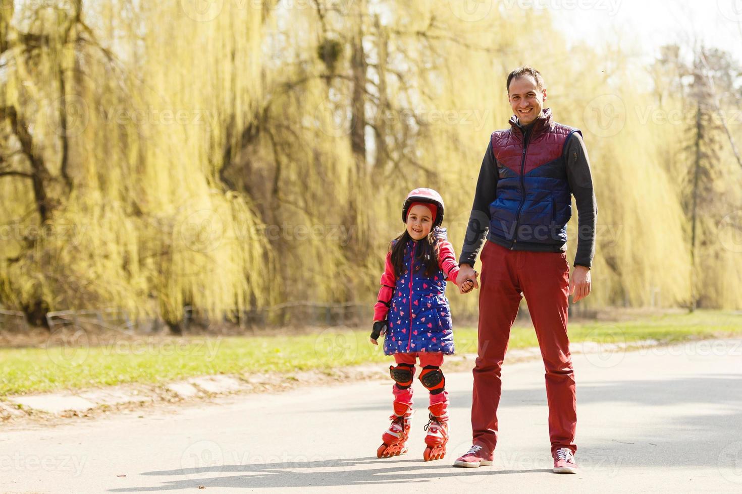 um pai ensinando sua filha a patinar em um parque num dia de verão. bom fim de semana. Dia dos Pais foto