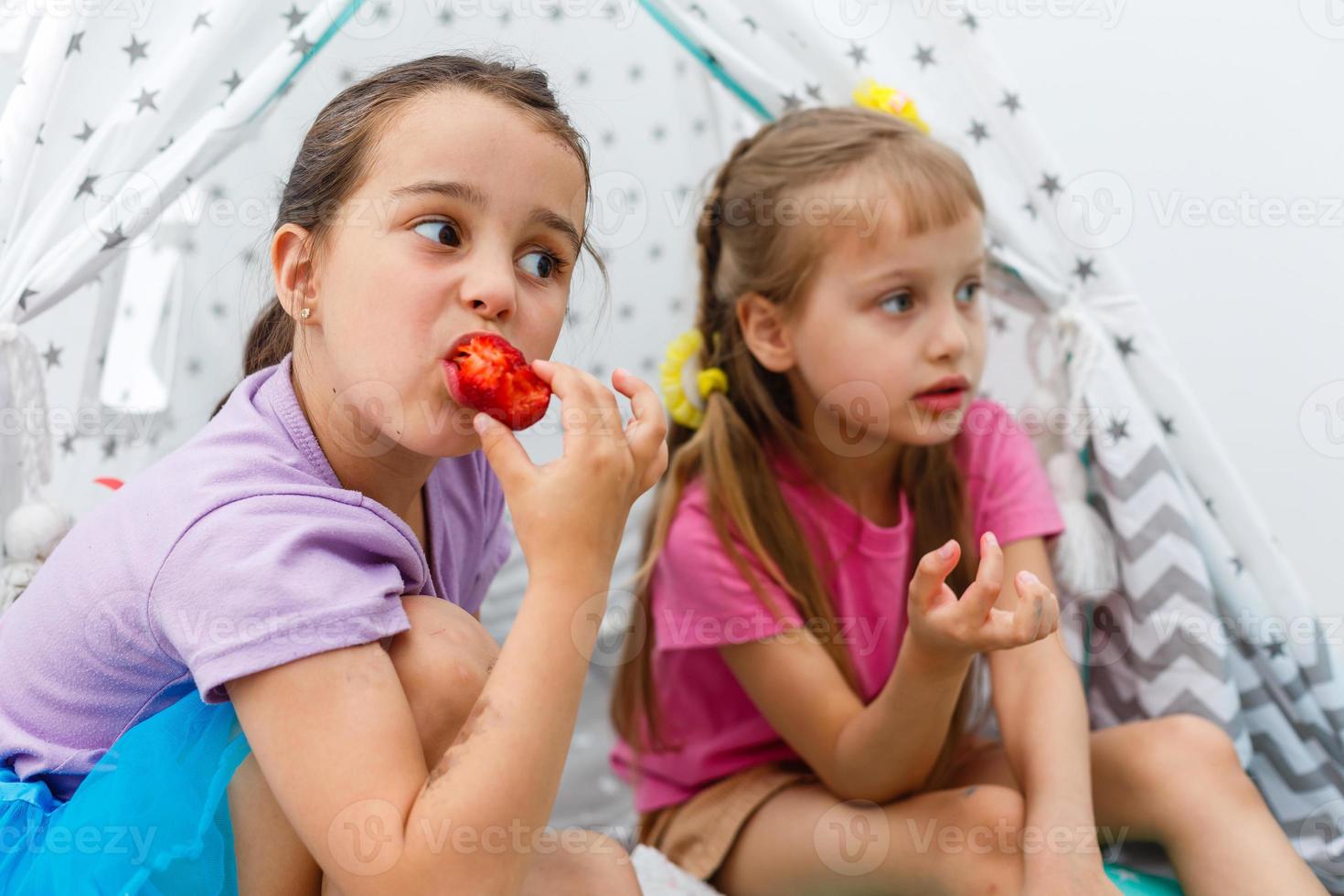 duas meninas comendo morangos foto