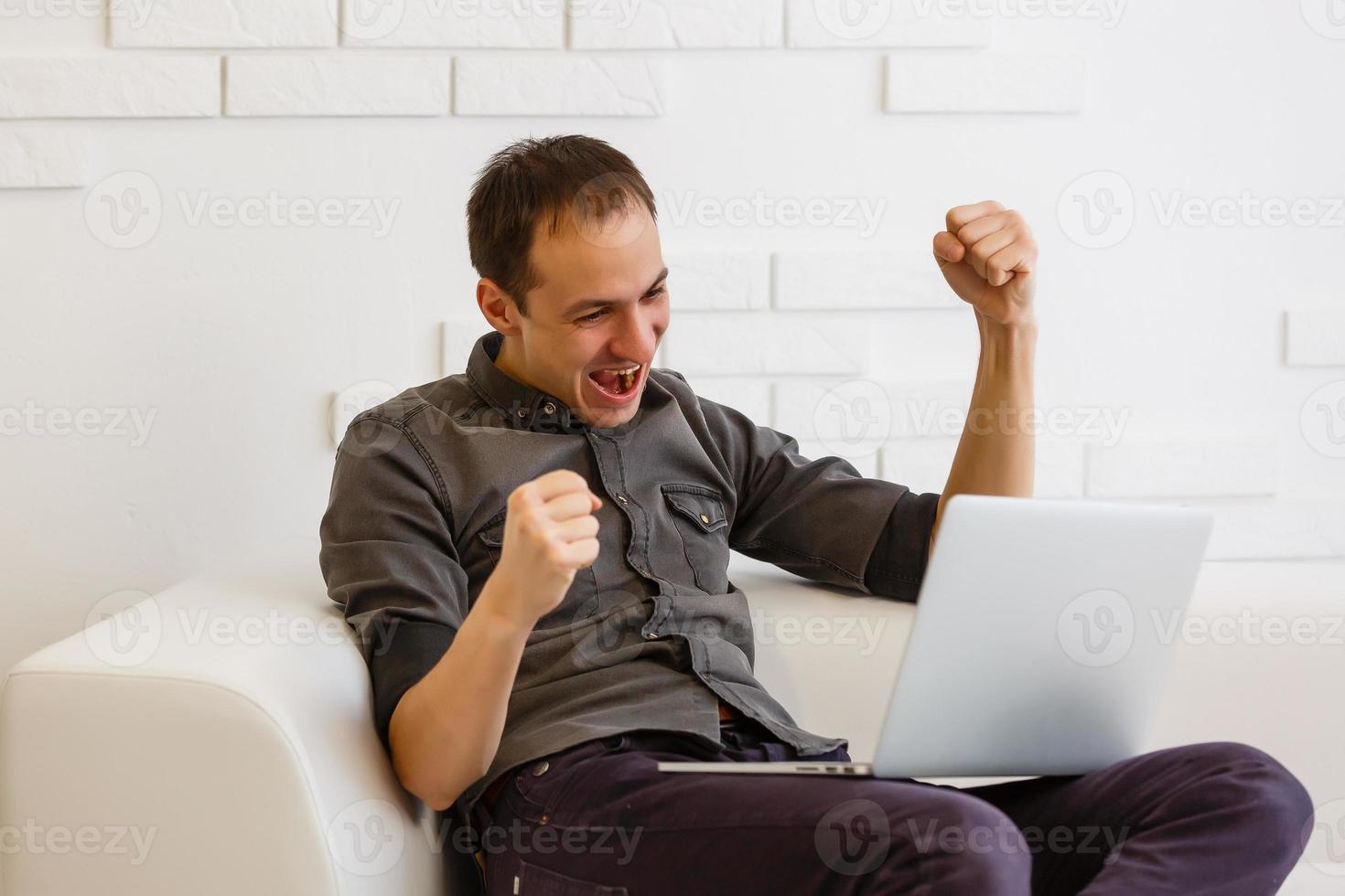 homem asiático feliz usando laptop na sala de estar. foto