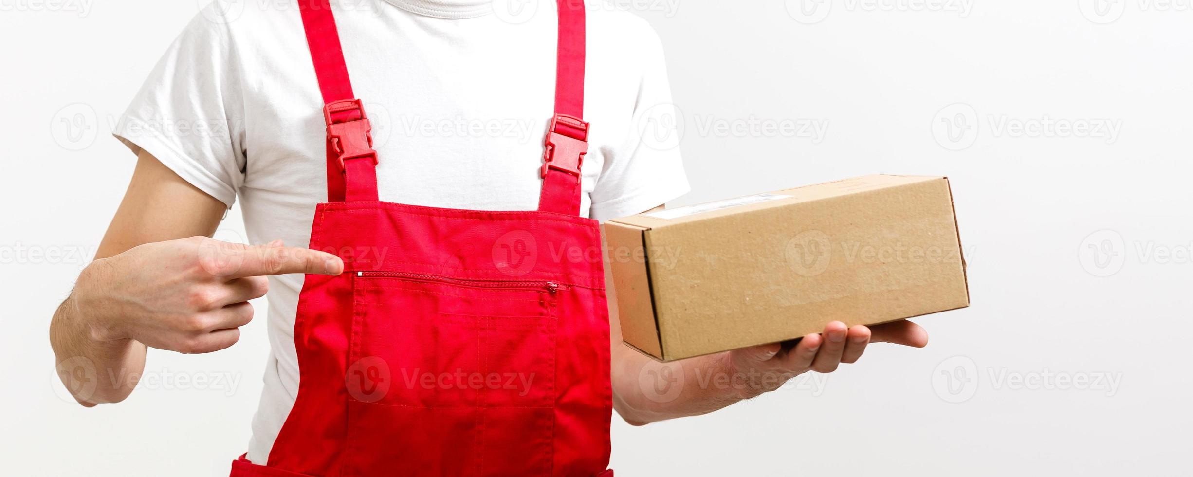 jovem sorridente entregador logístico em uniforme vermelho segurando a caixa no fundo branco foto