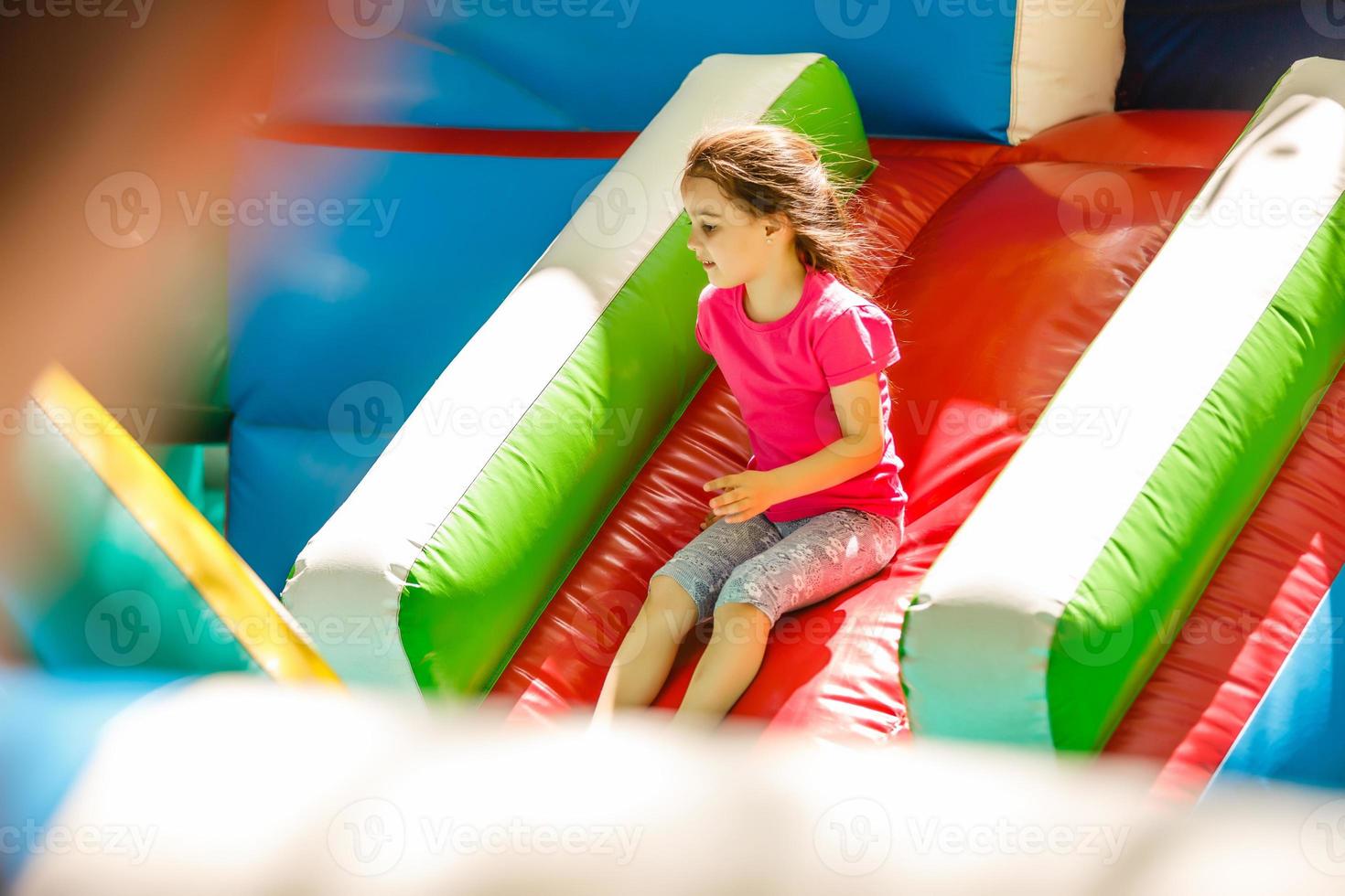 menina deslizando em um escorregador inflável foto