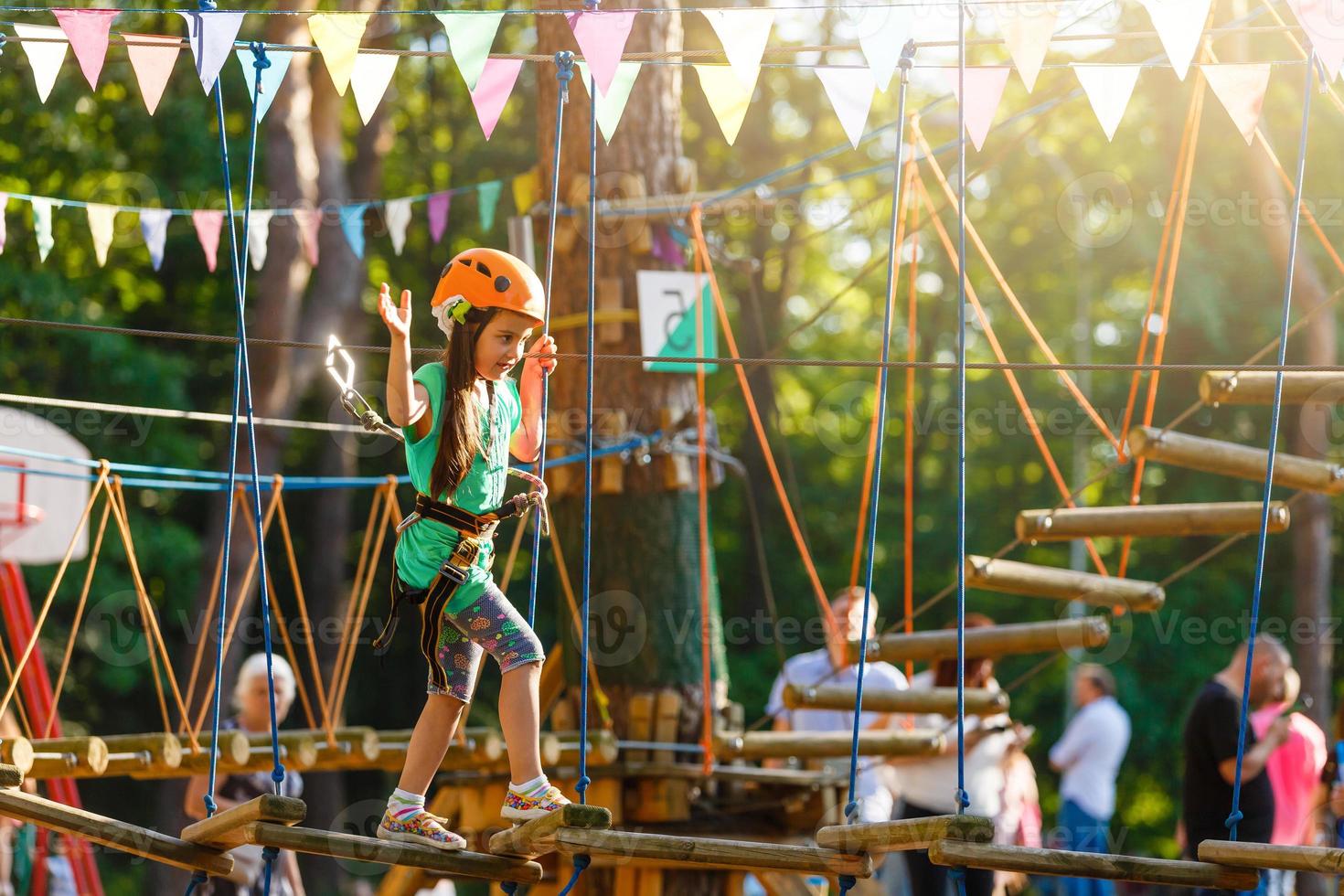 adorável menina aproveitando seu tempo na escalada do parque de aventura em um dia quente e ensolarado de verão. atividades de verão para crianças pequenas. criança se divertindo nas férias escolares. foto