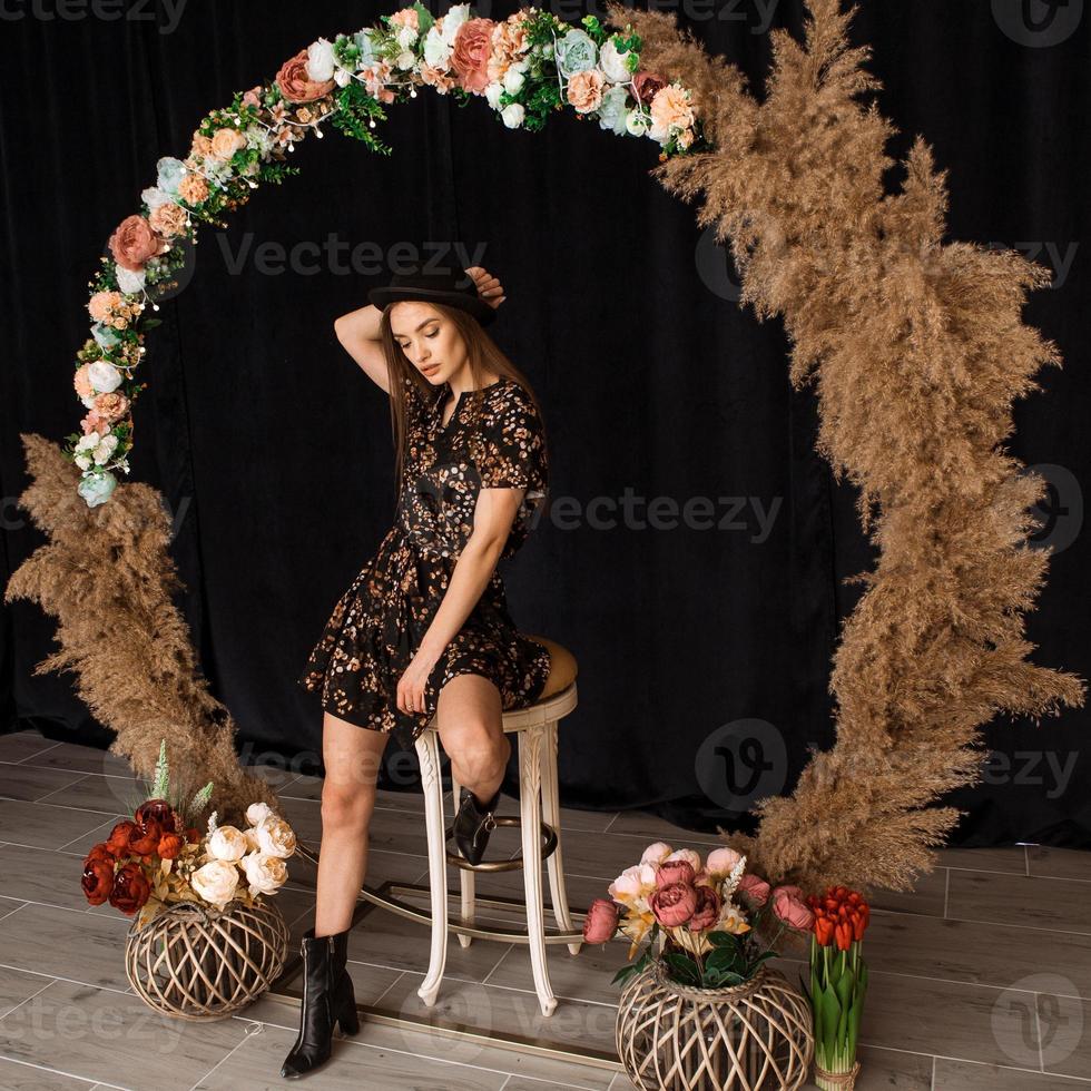 linda mulher posando no círculo de madeira morta em vestido com estampa de flores foto