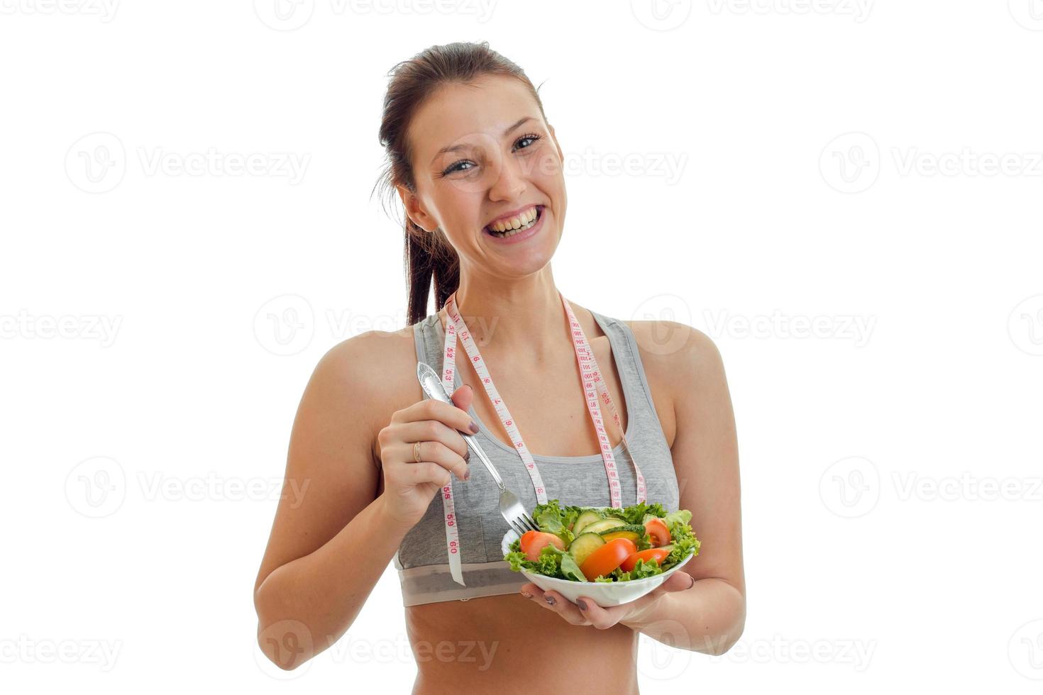 linda garota sorridente segurando um garfo de salada foto