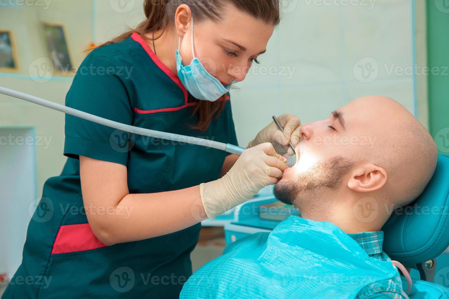 dentista de mulher bonita trata os dentes de seu paciente foto