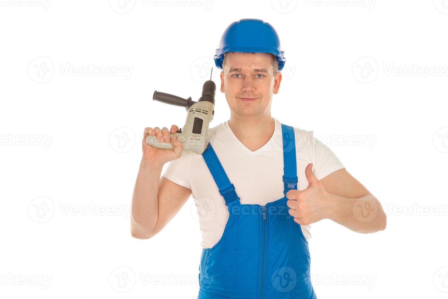 Construtor de uniforme azul com furadeira nas mãos foto