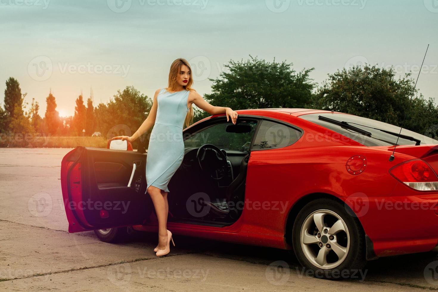 jovem sexy de salto alto perto de um carro vermelho foto