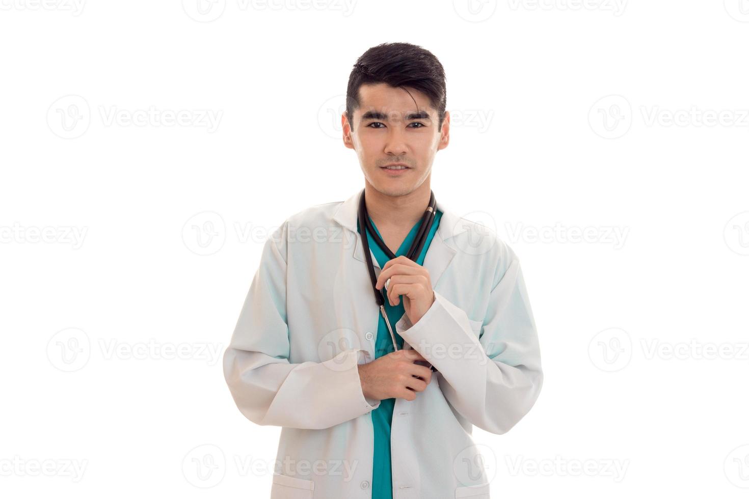 jovem médico masculino com estetoscópio em uniforme posando isolado no fundo branco foto