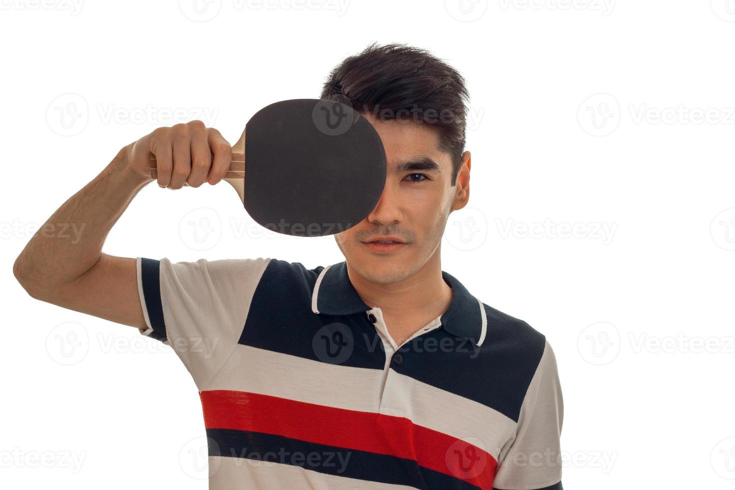 belo esportista praticando tênis de mesa com raquete nas mãos e olhando para a câmera isolada no fundo branco foto