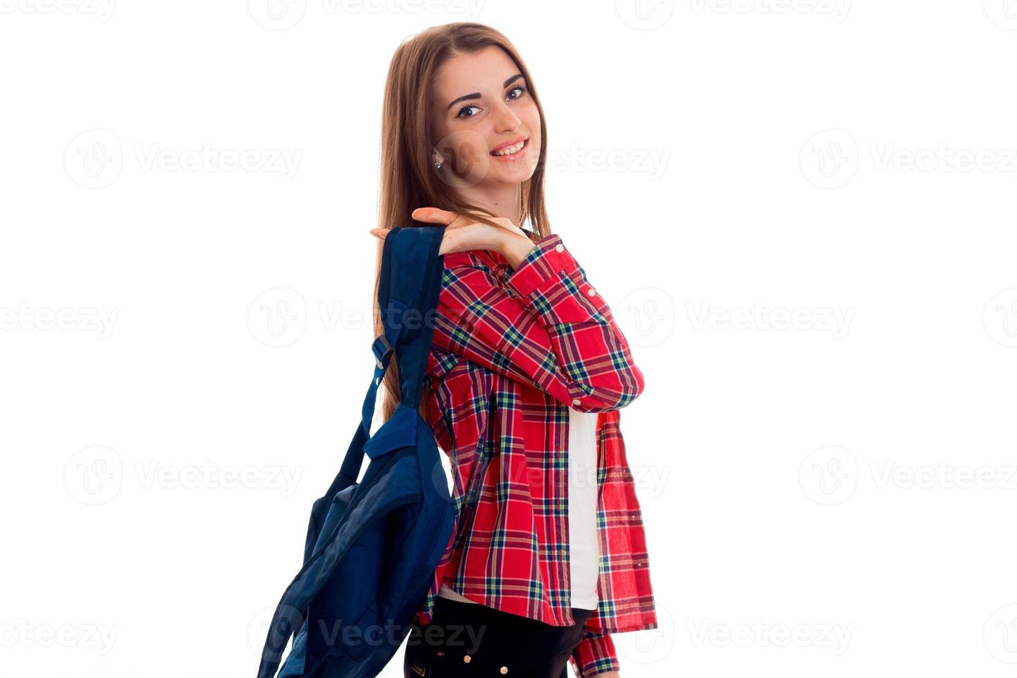 uma jovem de camisa xadrez vermelha e com uma carteira nos ombros de arquibancadas de lado e sorrindo foto
