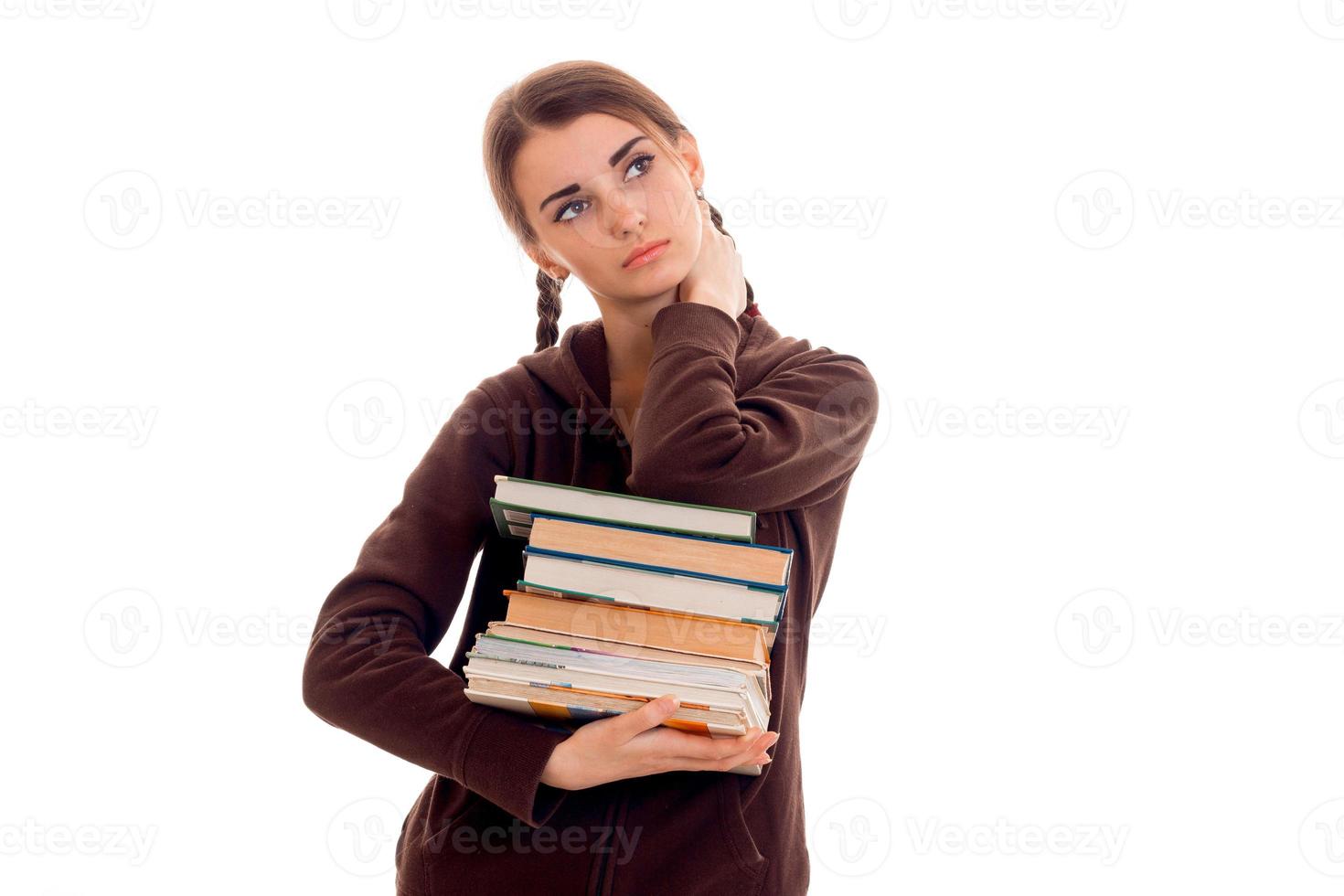 menina adolescente com tranças na jaqueta olha para cima e segura muitos livros foto