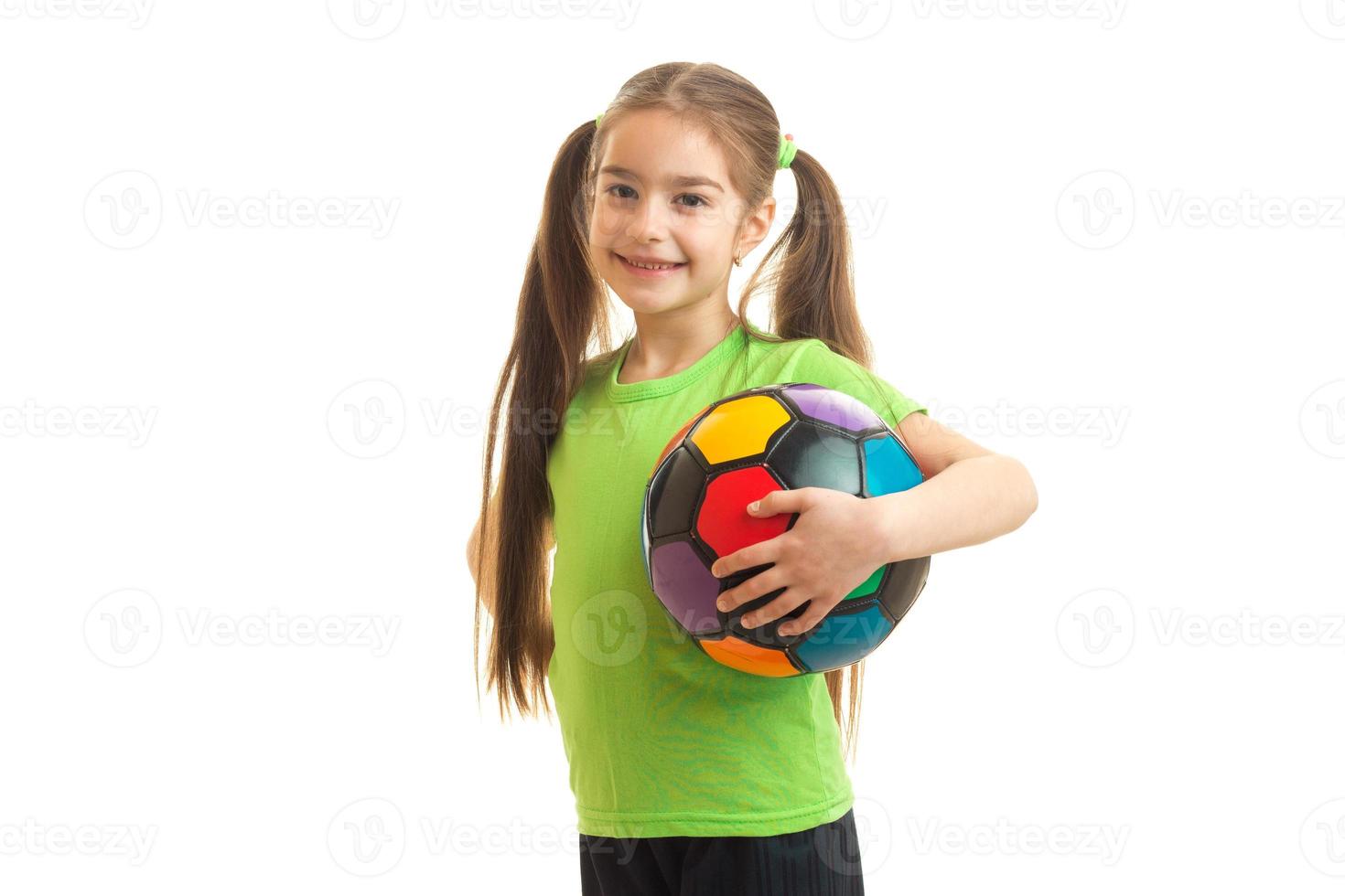 garotinha com bola de futebol na mão sorrindo para a câmera foto