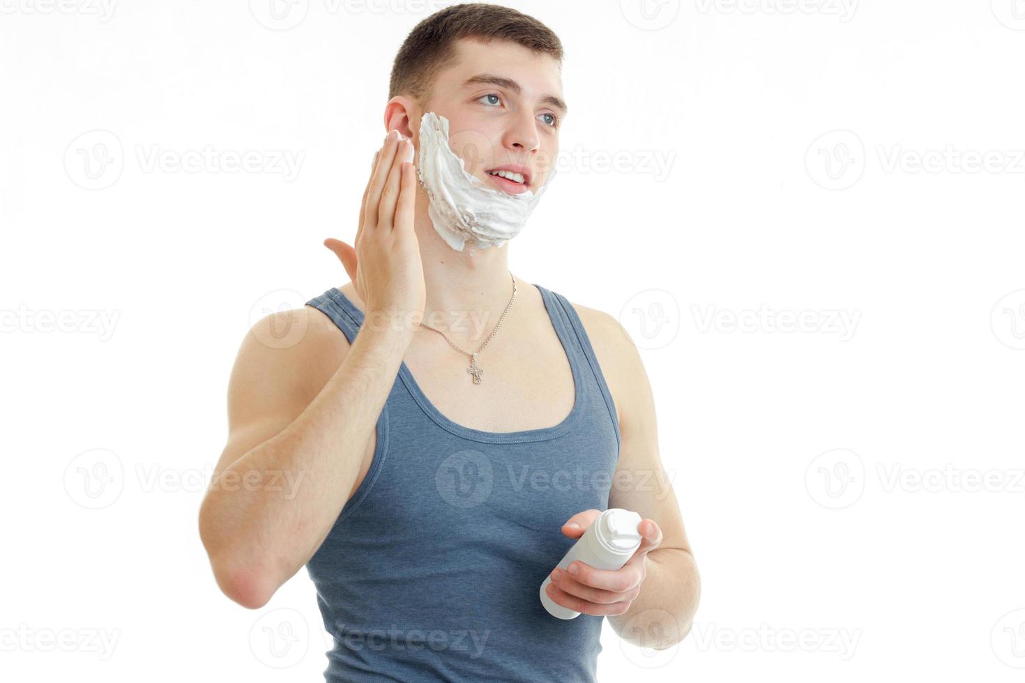 jovem se preparando para fazer a barba com espuma foto