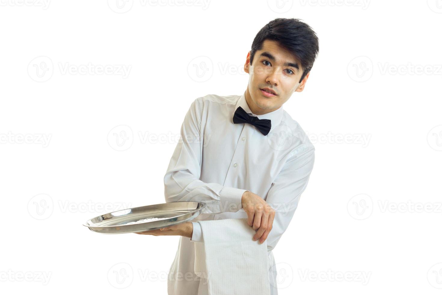 garçom jovem bonito em uma camisa branca com cabelo preto e inclinou-se para o lado e segurando uma bandeja de comida foto