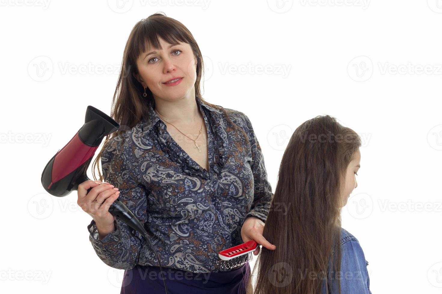 mãe com secador de cabelo faz um penteado para sua filha foto