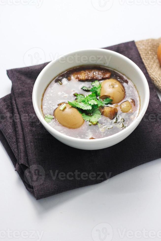 a comida tailandesa que chamamos de ovo e carne de porco em molho marrom doce é servida em um copo branco. em um restaurante na tailândia foto