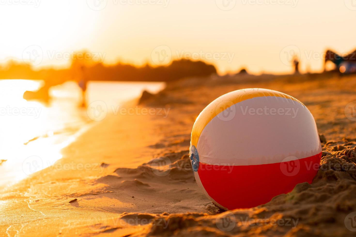 bola de praia à beira-mar ao pôr do sol foto