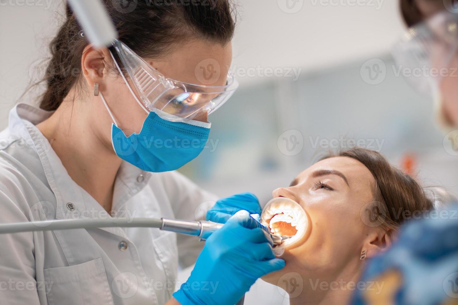 dentista e assistente tratam os dentes de um paciente foto