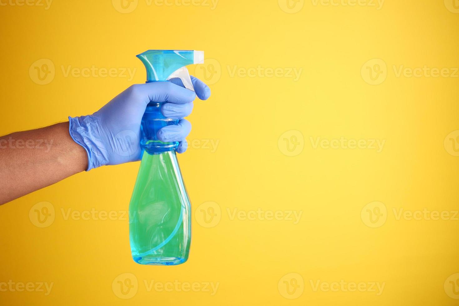 segurando uma garrafa de plástico desinfetando contra fundo amarelo foto