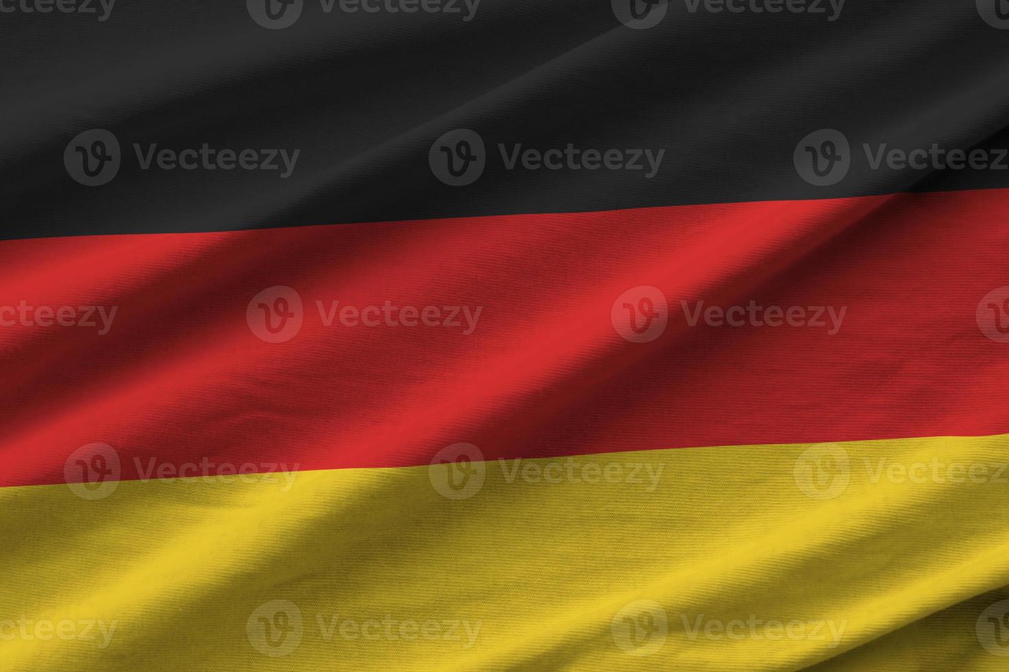 bandeira da alemanha com grandes dobras acenando perto sob a luz do estúdio dentro de casa. os símbolos e cores oficiais no banner foto