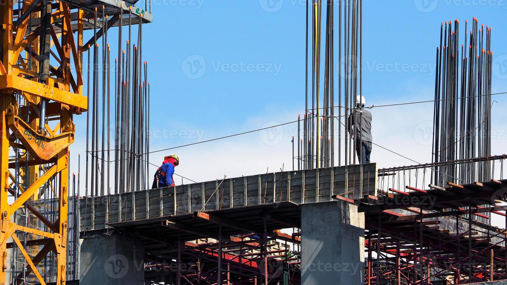 engenheiro e trabalhadores em alto canteiro de obras e textura de aço e cimento e céu azul. foto