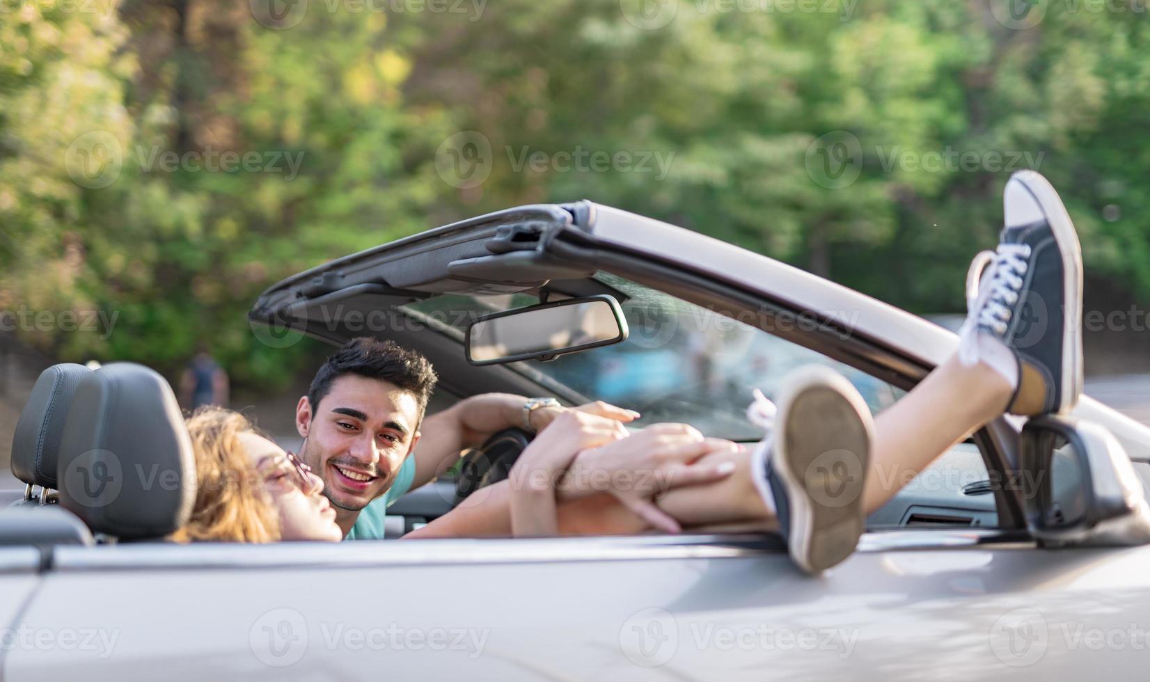 amigos se divertindo na viagem de carro ao redor do mundo. casal apaixonado com os braços para cima em um carro conversível. foto