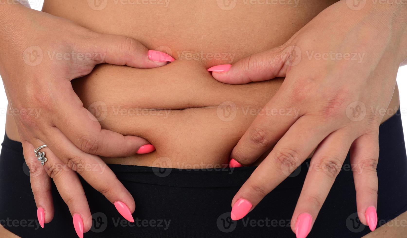 vista do meio de uma mulher beliscando a pele para teste de gordura. isolado no fundo branco. foto