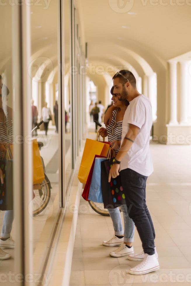 retrato de um jovem casal caucasiano alegre homem e mulher segurando muitos sacos de papel depois de fazer compras enquanto caminhava e conversava na rua. casal de família feliz com pacotes ao ar livre. conceito de compra foto