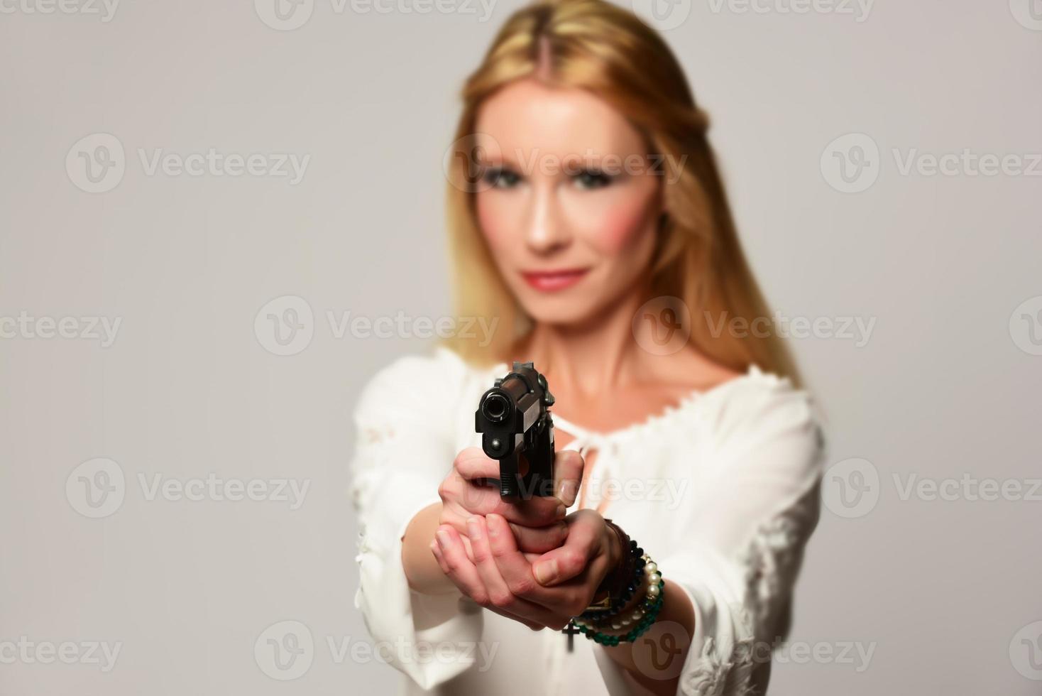 bela agente secreta segurando a arma de mão, isolada no branco foto