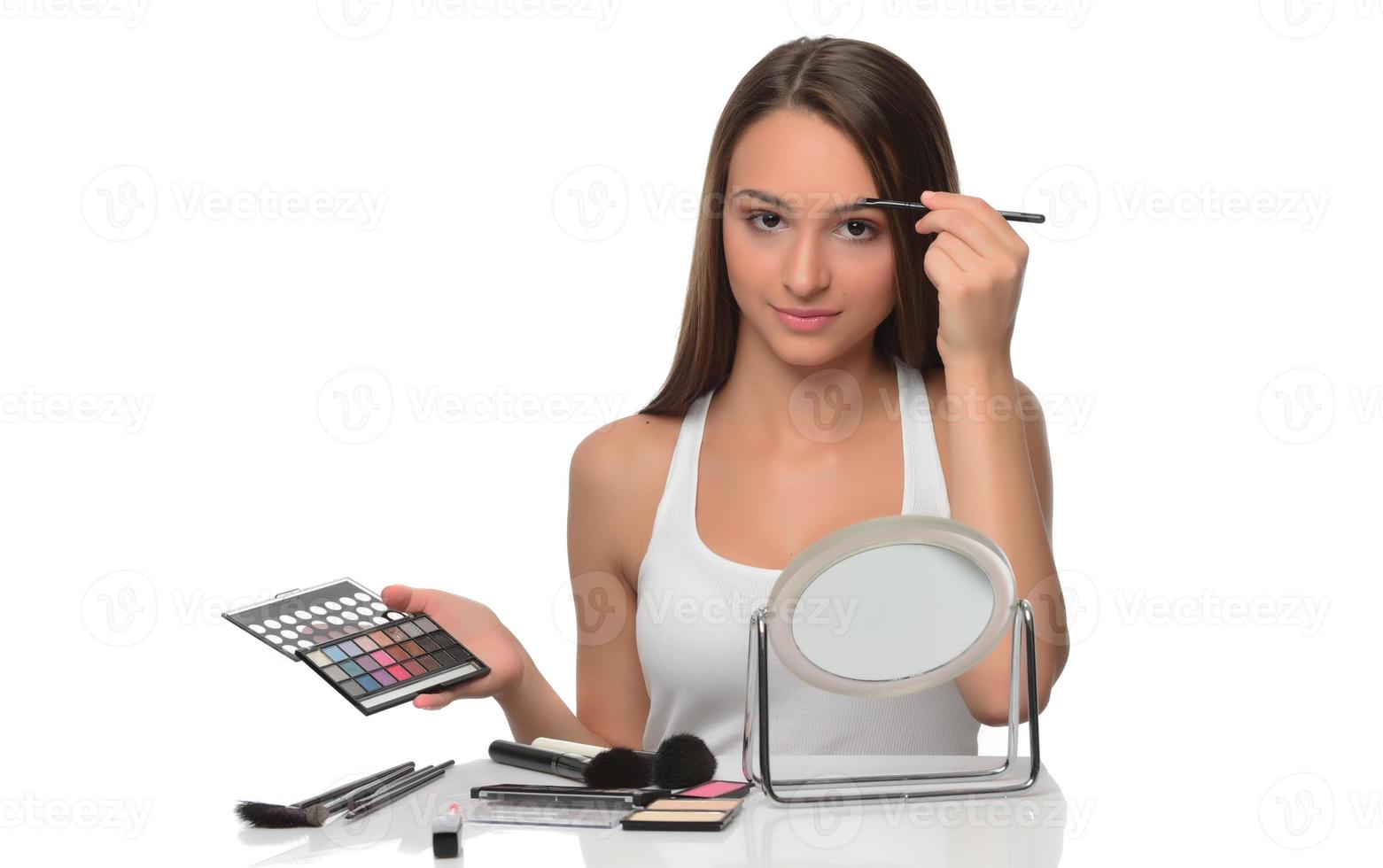 maquiador aplica sombra nos olhos. rosto de mulher bonita. mão de visagista, pintando cosméticos de jovem modelo de beleza. maquiagem em processo foto