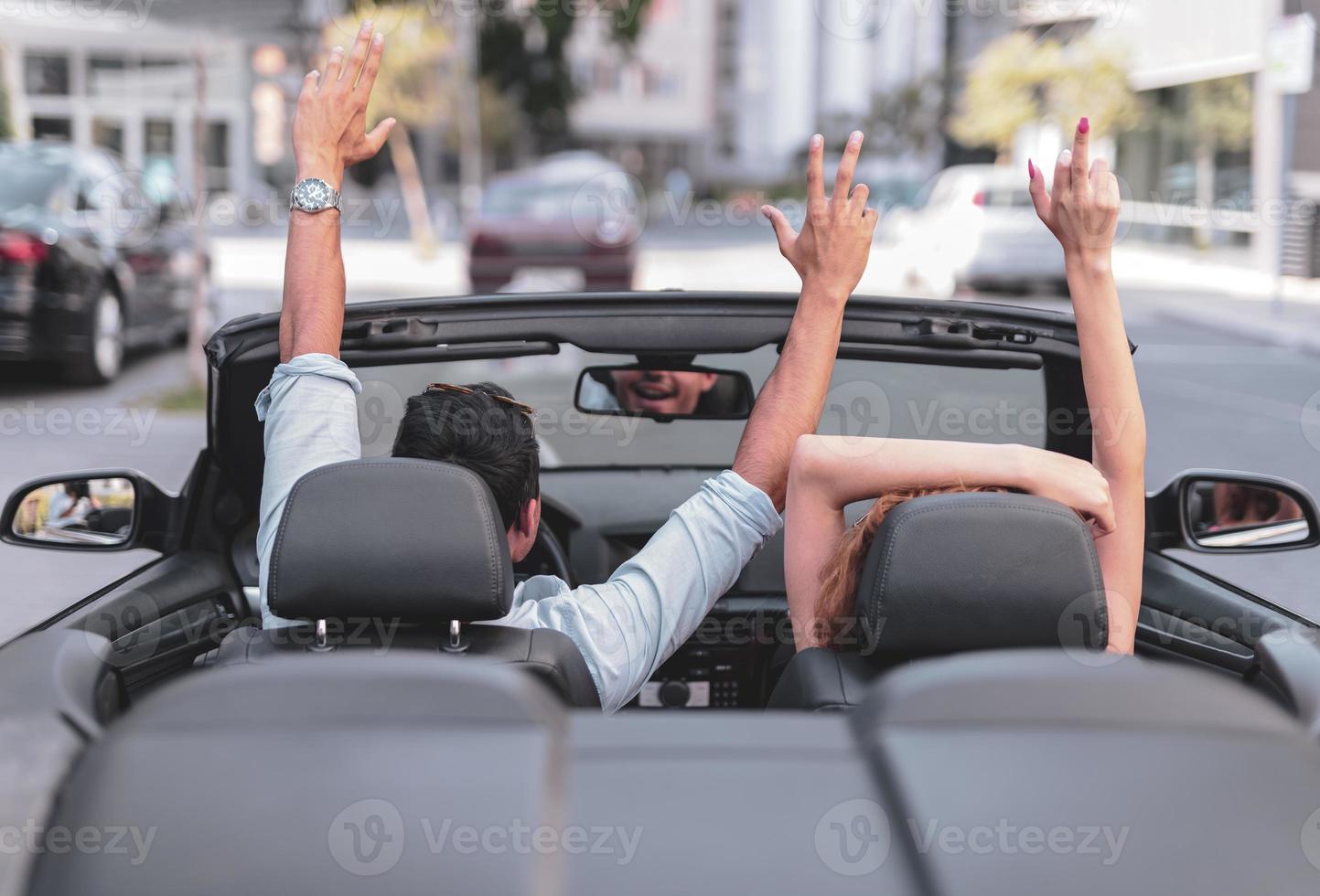 amigos se divertindo na viagem de carro ao redor do mundo. casal apaixonado com os braços para cima em um carro conversível. foto