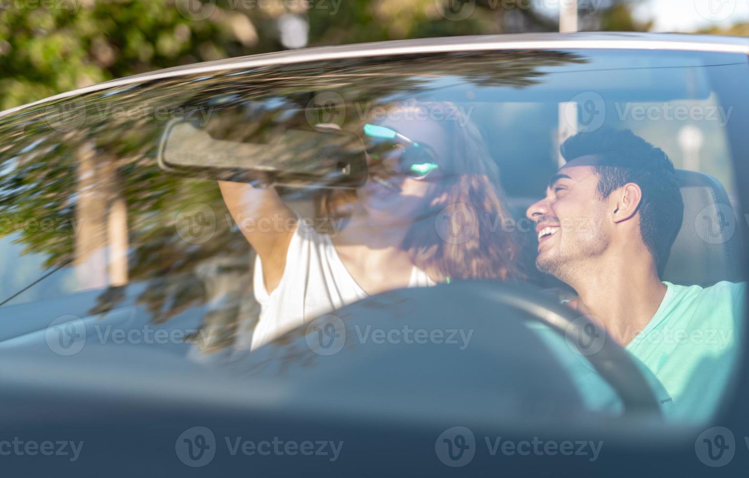 amigos se divertindo na viagem de carro ao redor do mundo. casal apaixonado com os braços para cima em um carro conversível. foto