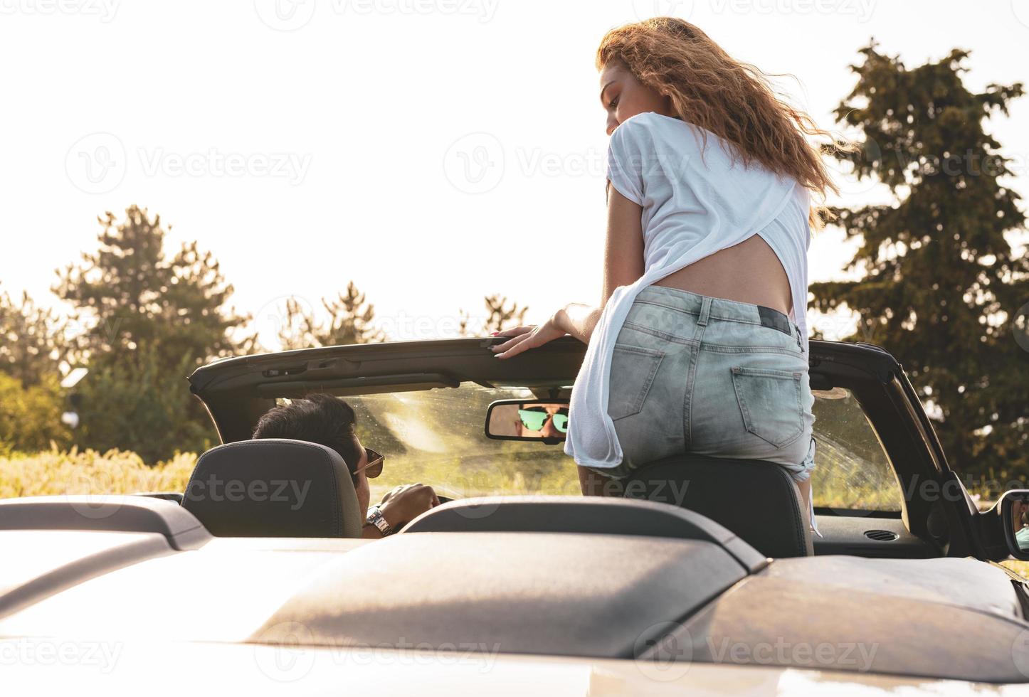 amigos se divertindo na viagem de carro ao redor do mundo. casal apaixonado com os braços para cima em um carro conversível. foto