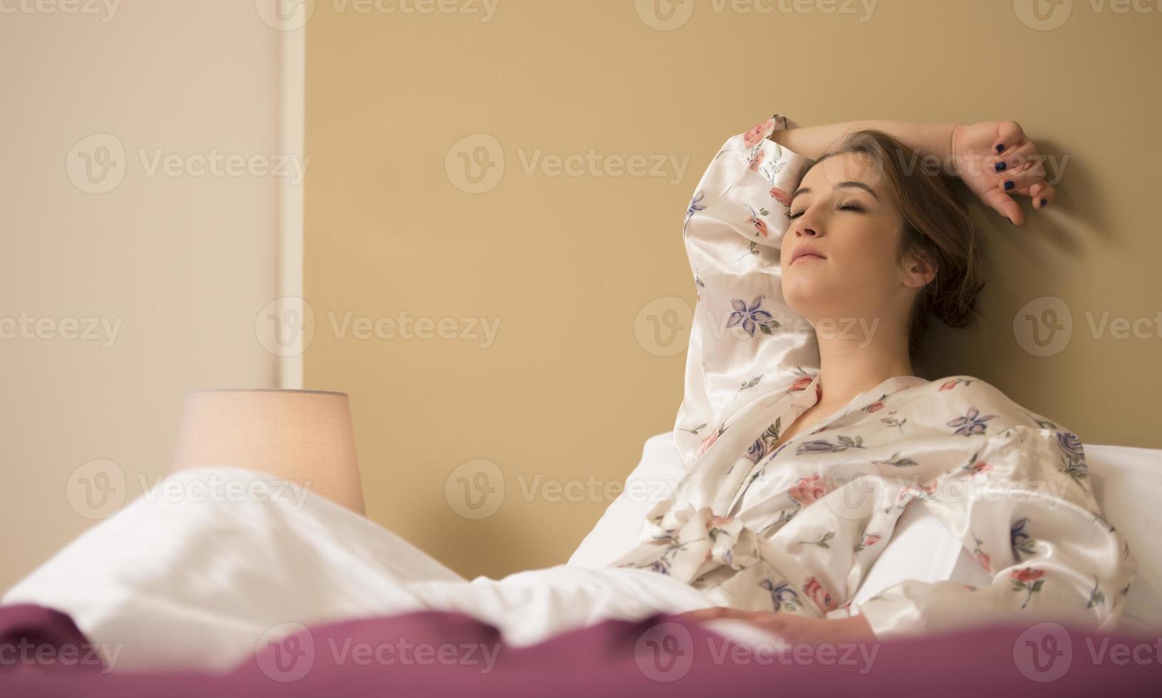 pacífica serena bela jovem vestindo pijama deitado dormindo relaxando dormindo na cama branca aconchegante no travesseiro macio descansando foto