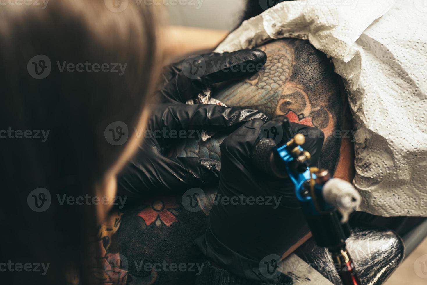 feche a máquina de tatuagem. mulher criando foto na mão com ele no salão