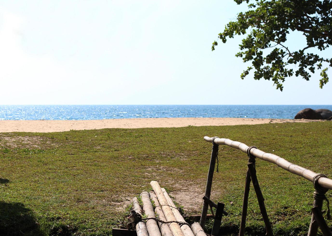 mar azul e praia branca, ponte de bambu atravessando a praia foto