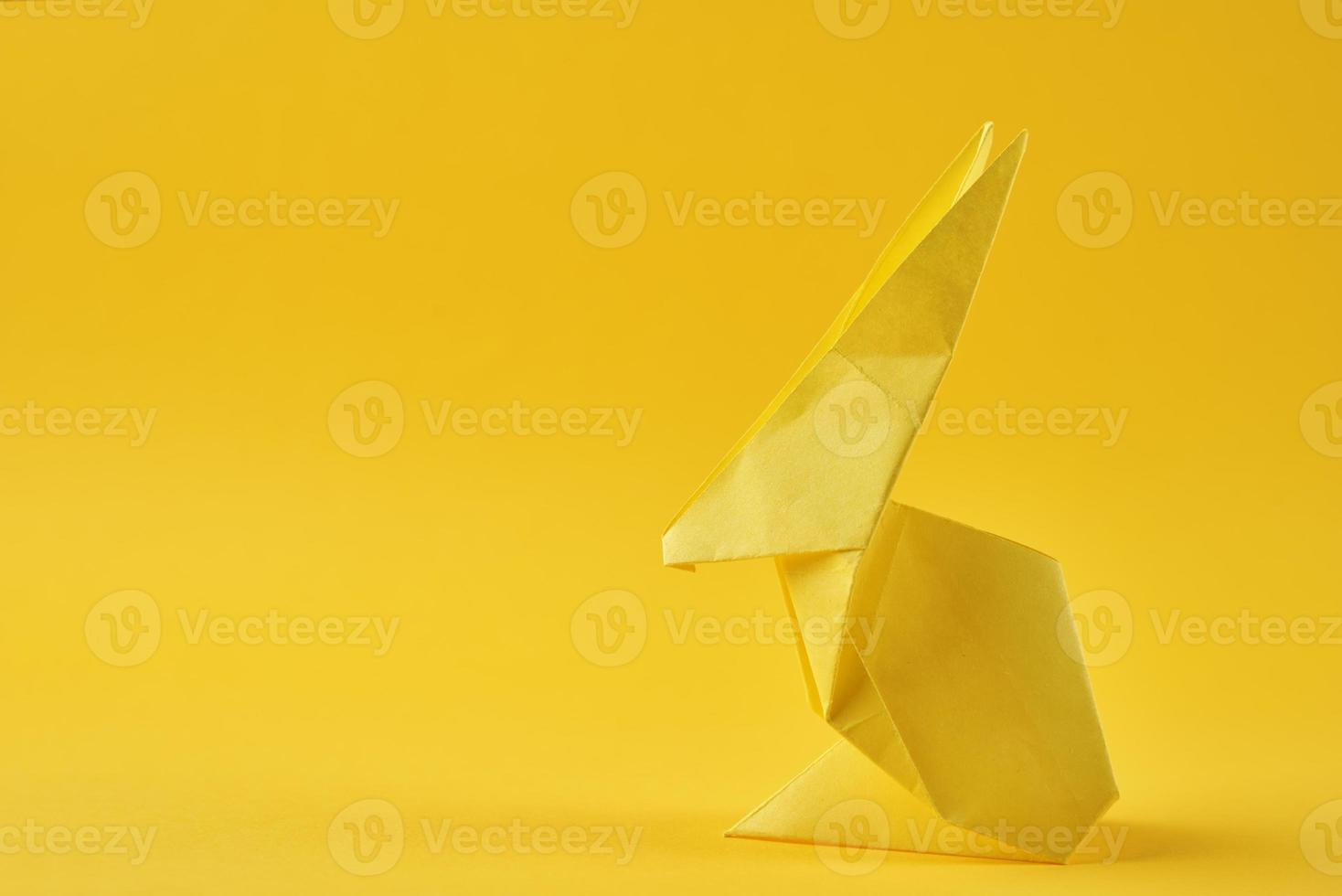 coelho esater de origami de papel em um fundo amarelo. conceito de celebração de páscoa foto