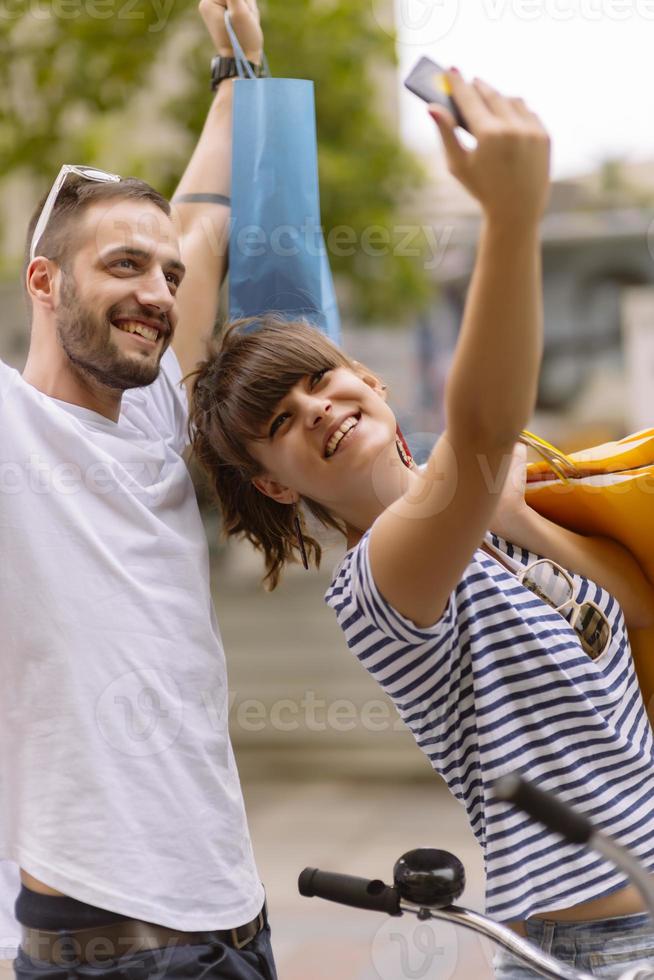 retrato de um jovem casal caucasiano alegre homem e mulher segurando muitos sacos de papel depois de fazer compras enquanto caminhava e conversava na rua. casal de família feliz com pacotes ao ar livre. conceito de compra foto