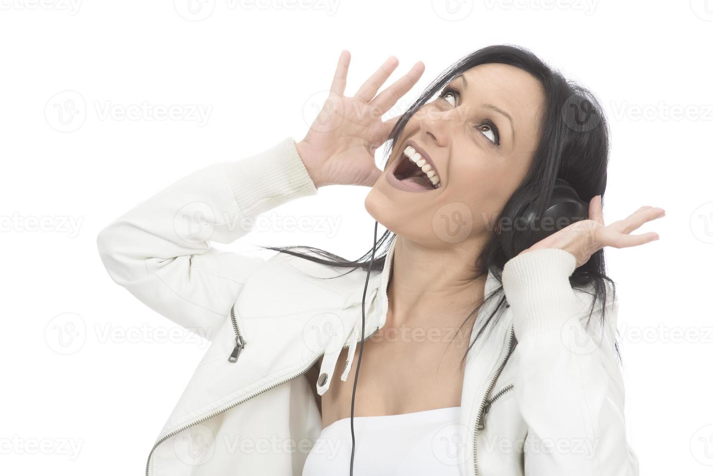 linda garota moderna cantando música favorita, ouvindo música em fones de ouvido sem fio, sorrindo e dançando foto